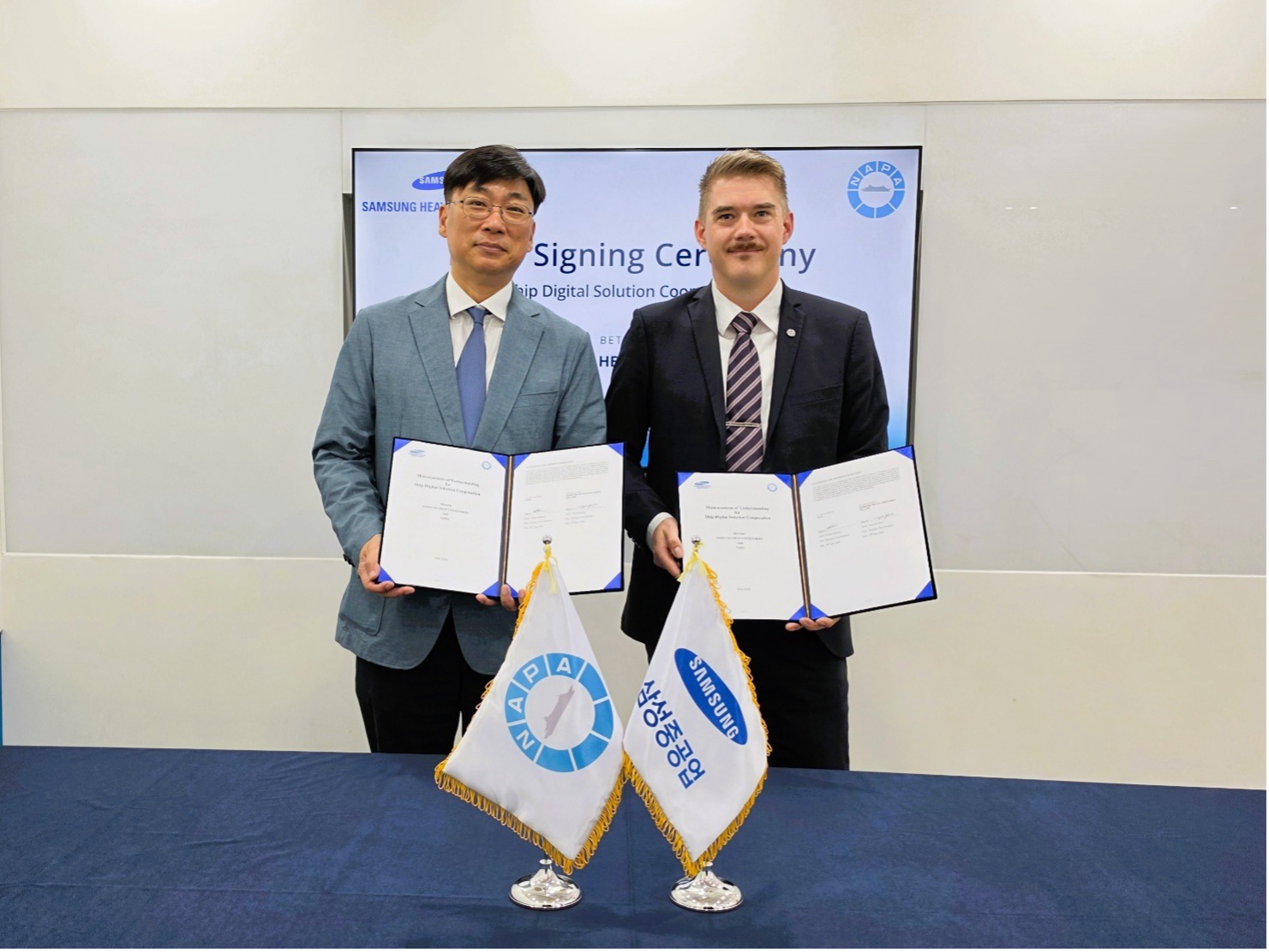 HyunJoe Kim of Samsung Heavy Industries and Pekka Pakkanen of NAPA holding signed partnership agreements at a collaboration signing ceremony.